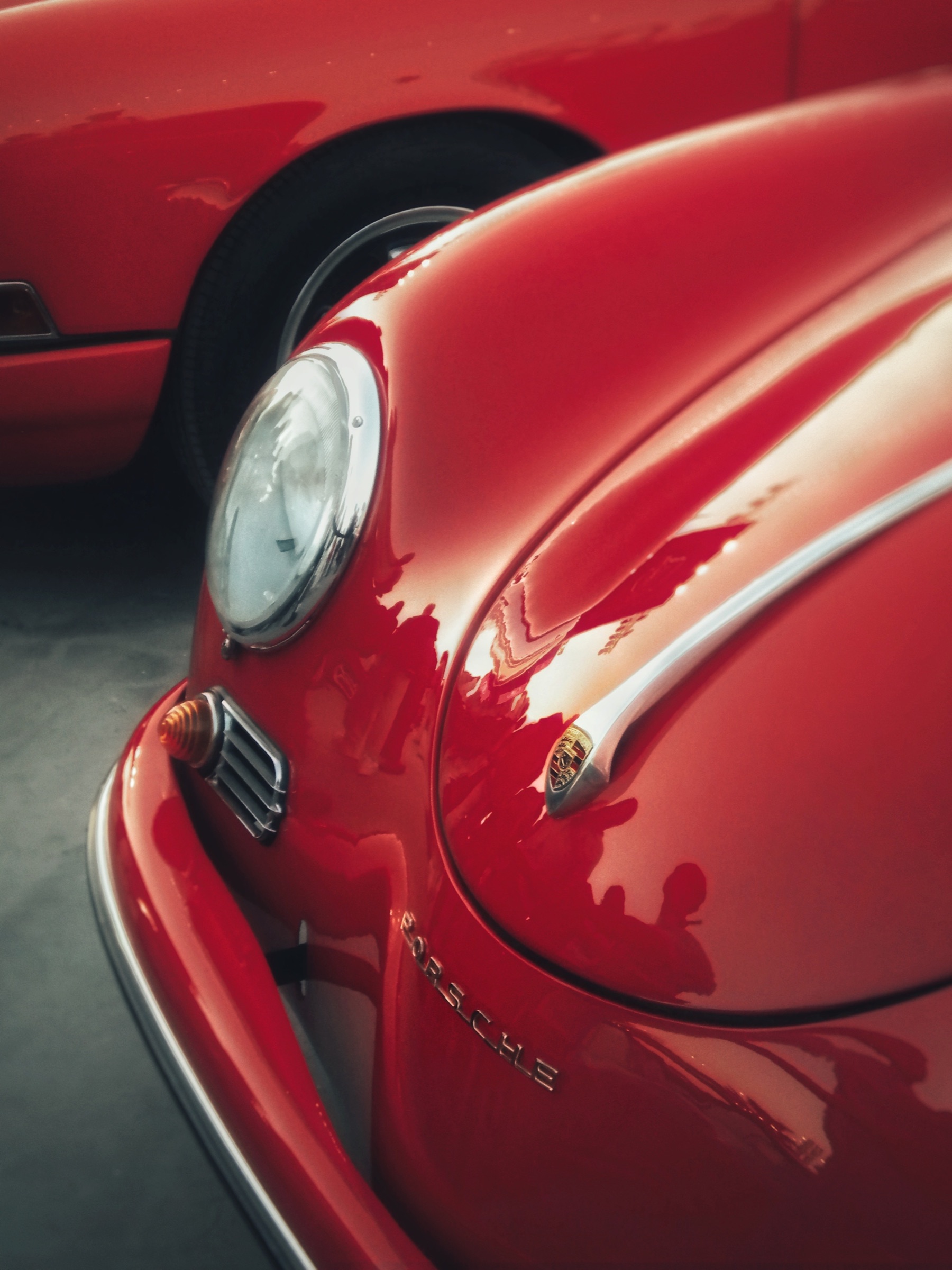Macro study of a vintage Porsche 356's headlight and hood in warm light